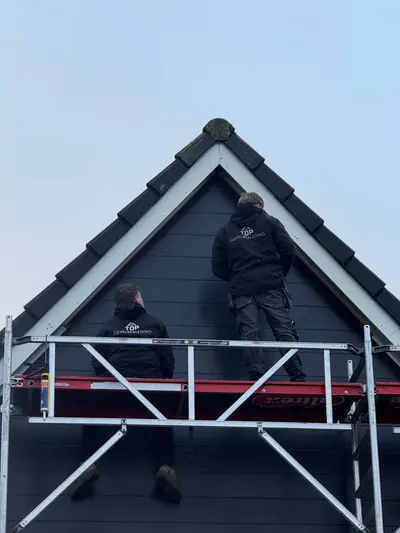Twee monteurs van Top Gevelbekleding bekleden een topgevel met donkere Keralit gevelbekleding